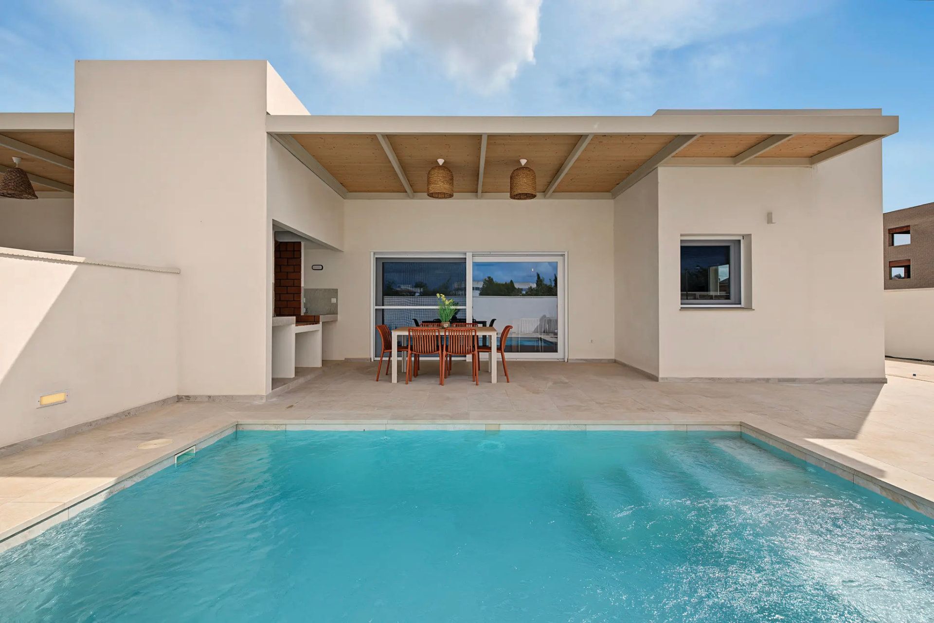 Piscina privada i façana blanca de la casa sota el cel blau